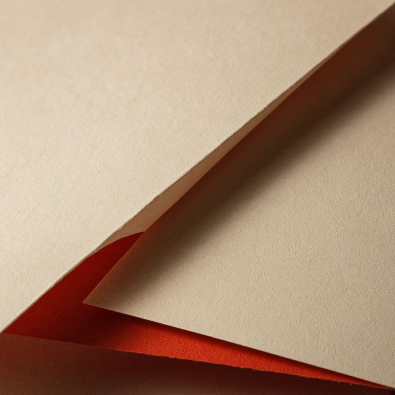 A folded cream sheet over a red one, close up