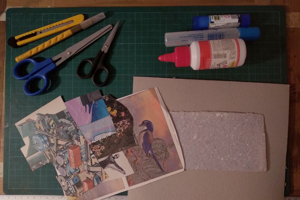 Scissors, craft knives, glue and paper scraps on a green cutting board