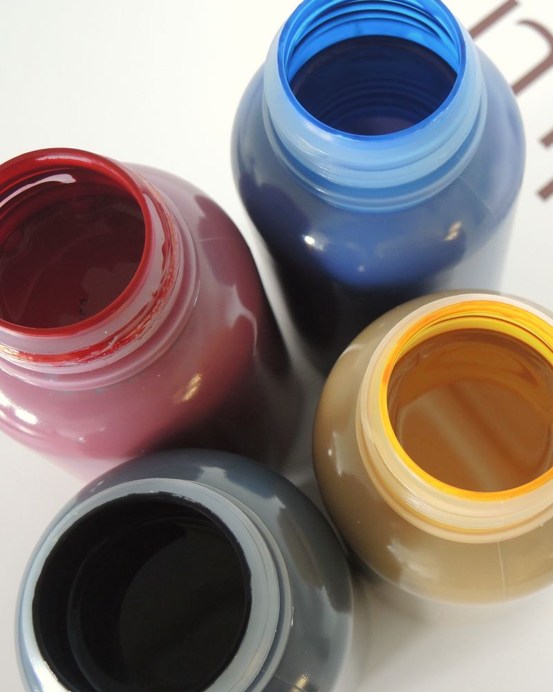 Open jars of red, blue, yellow and black printing ink