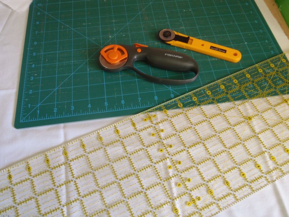 A green cutting mat with two rotary cutters and a clear ruler