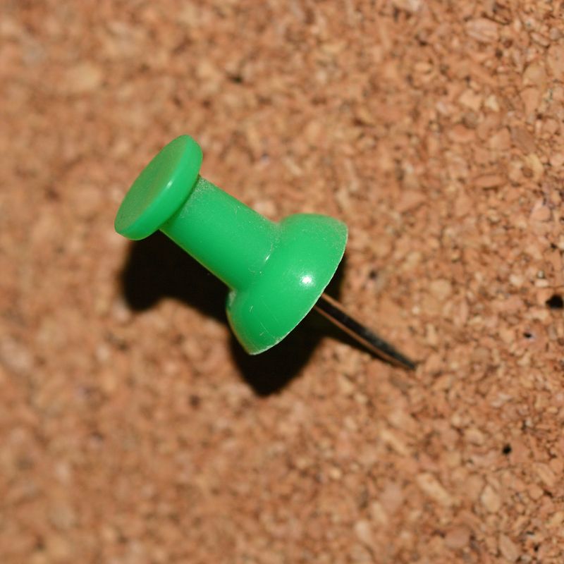 A green push pin in a cork board