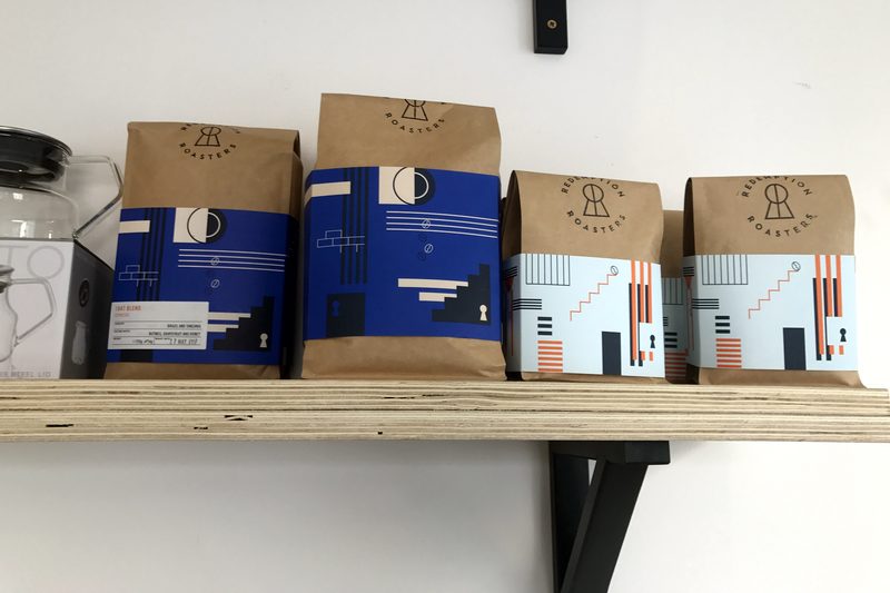 Paper coffee bags lined up on a wooden wall shelf