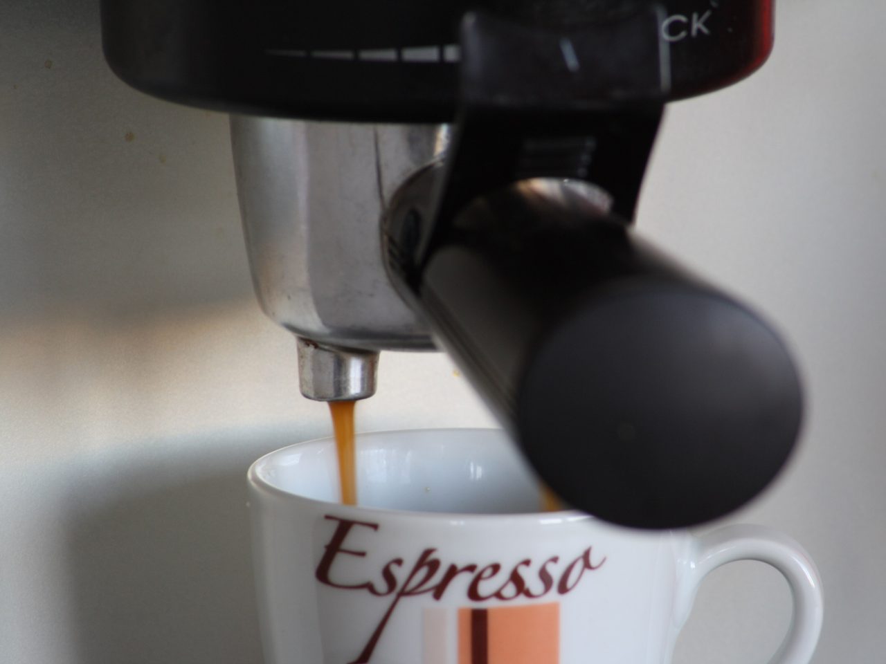 Espresso running from a portafilter spout into a white cup