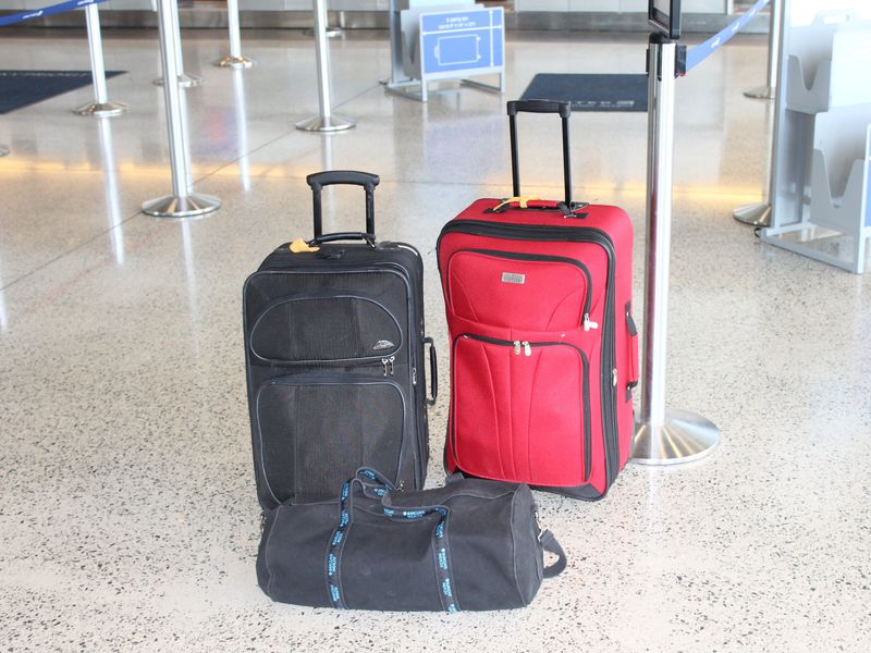 Two suitcases and a duffel bag waiting on an airport floor