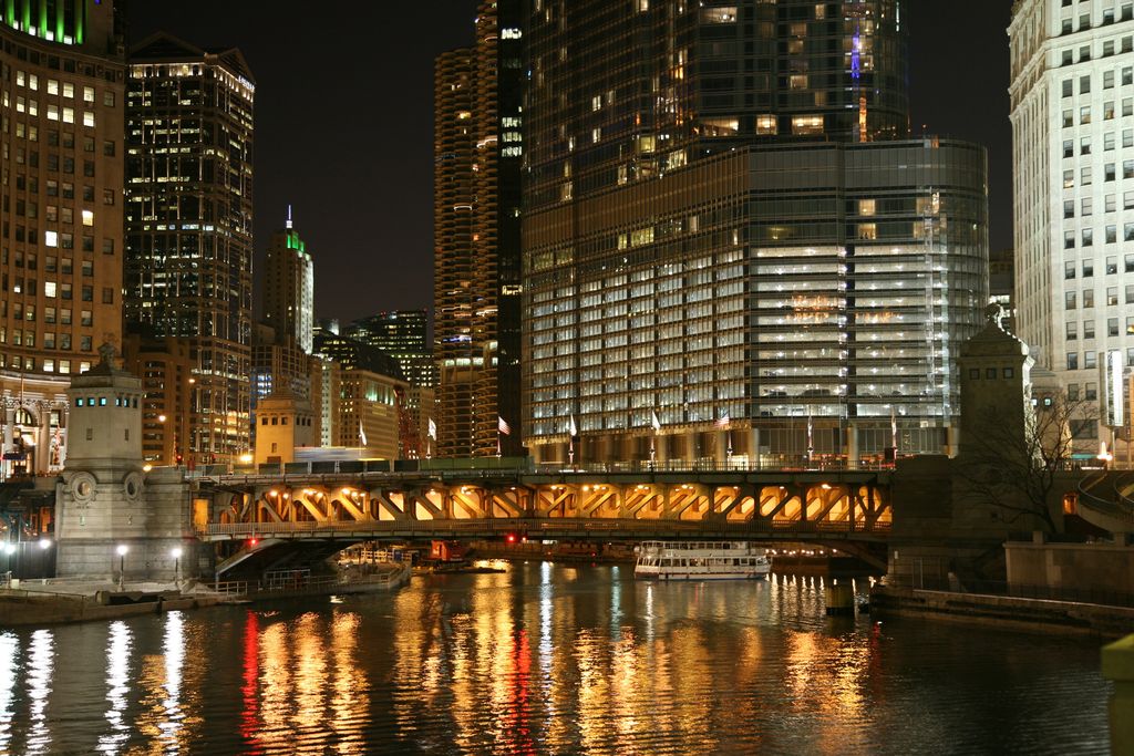 The Chicago River at night, with a lit bridge and towers reflected in the water