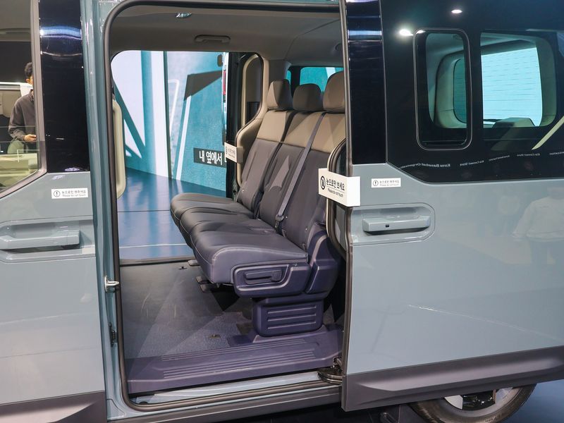 The open sliding door of a passenger van, with two rows of seats inside