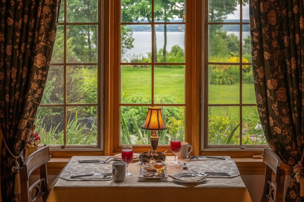 A breakfast table laid by a sunny window framed with curtains