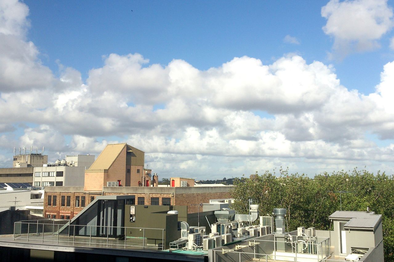 The view from an office window over city rooftops under a sky of white clouds