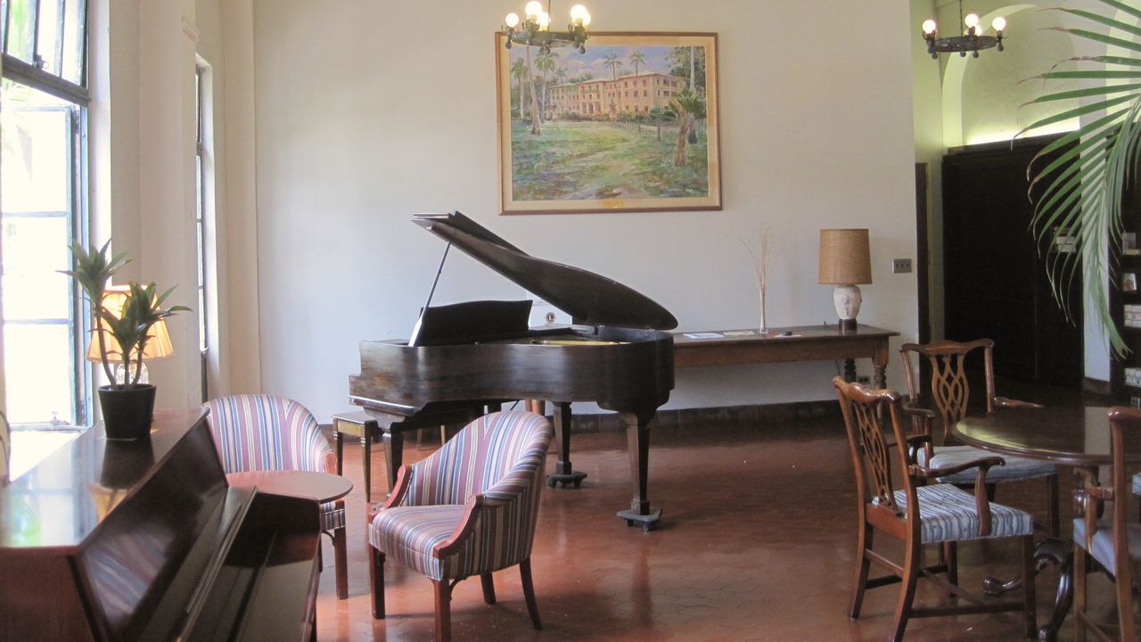 A lounge with a grand piano, armchairs and chandeliers
