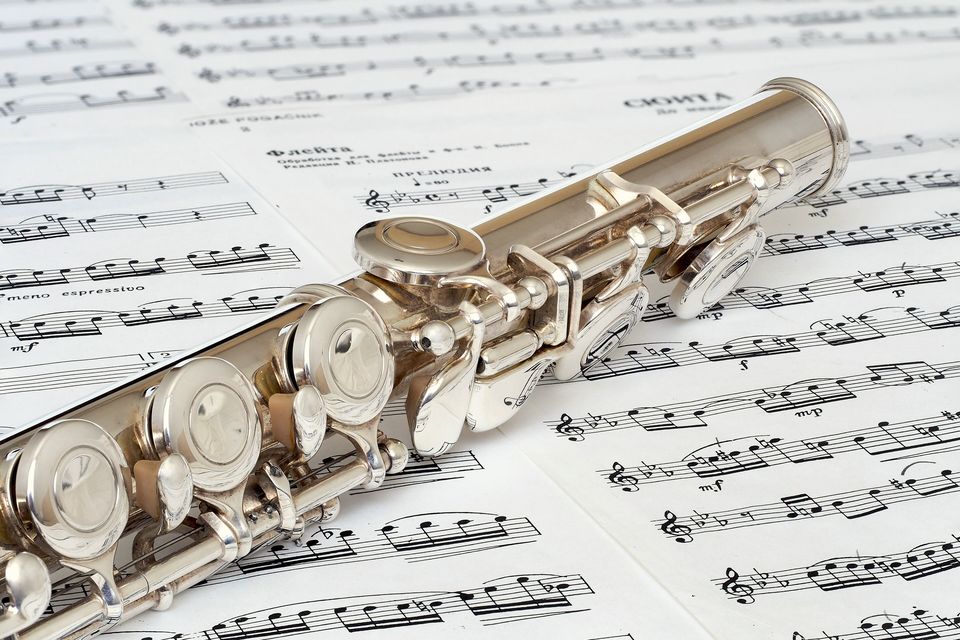 A silver flute lying across sheet music