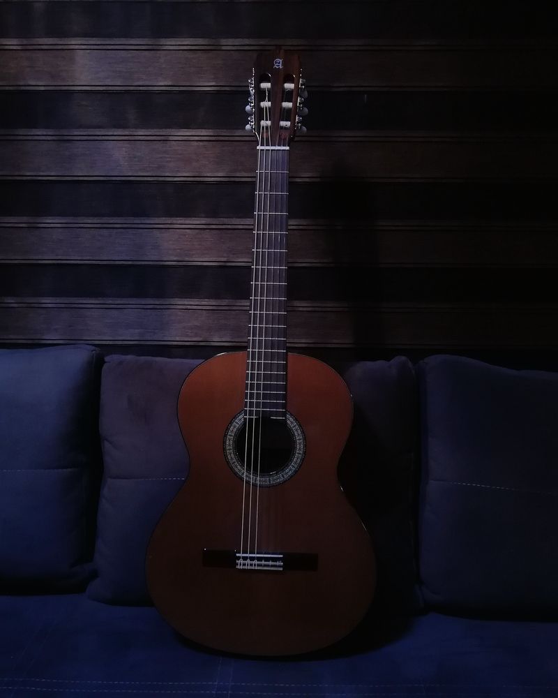 A classical guitar standing against a dark wall