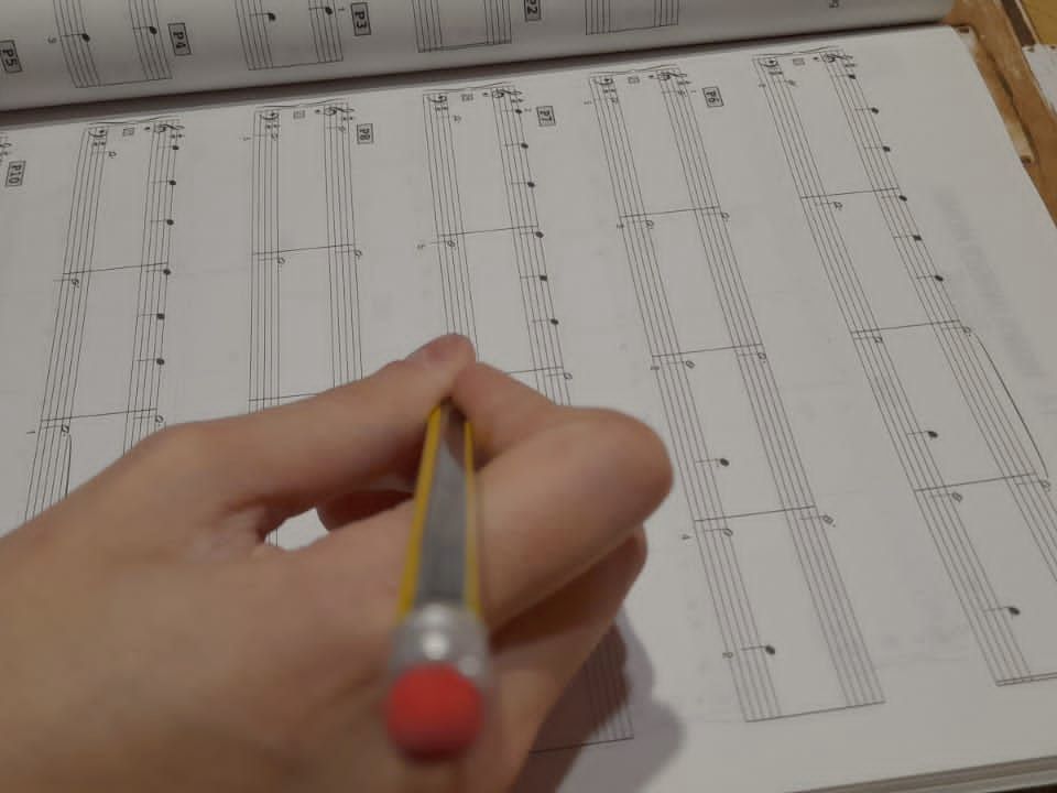 A hand writing in pencil on a page of music