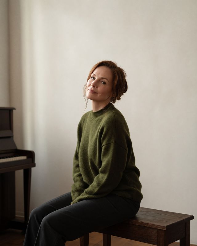 Elena Voss, seated in an olive sweater, with a calm smile.