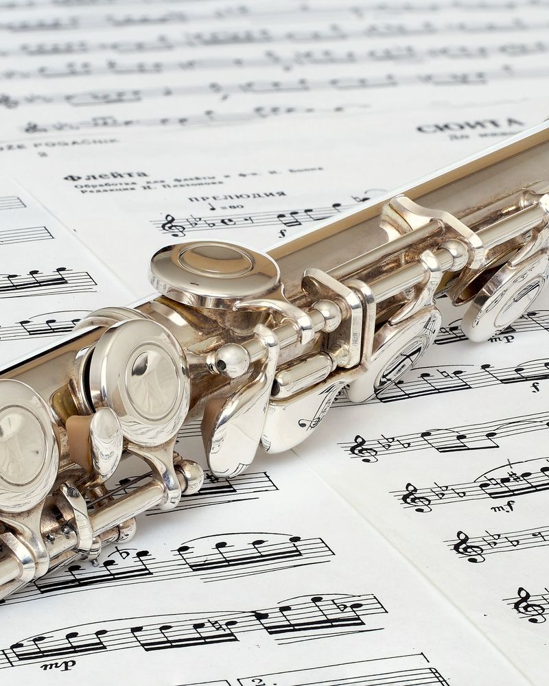A silver flute lying across sheet music