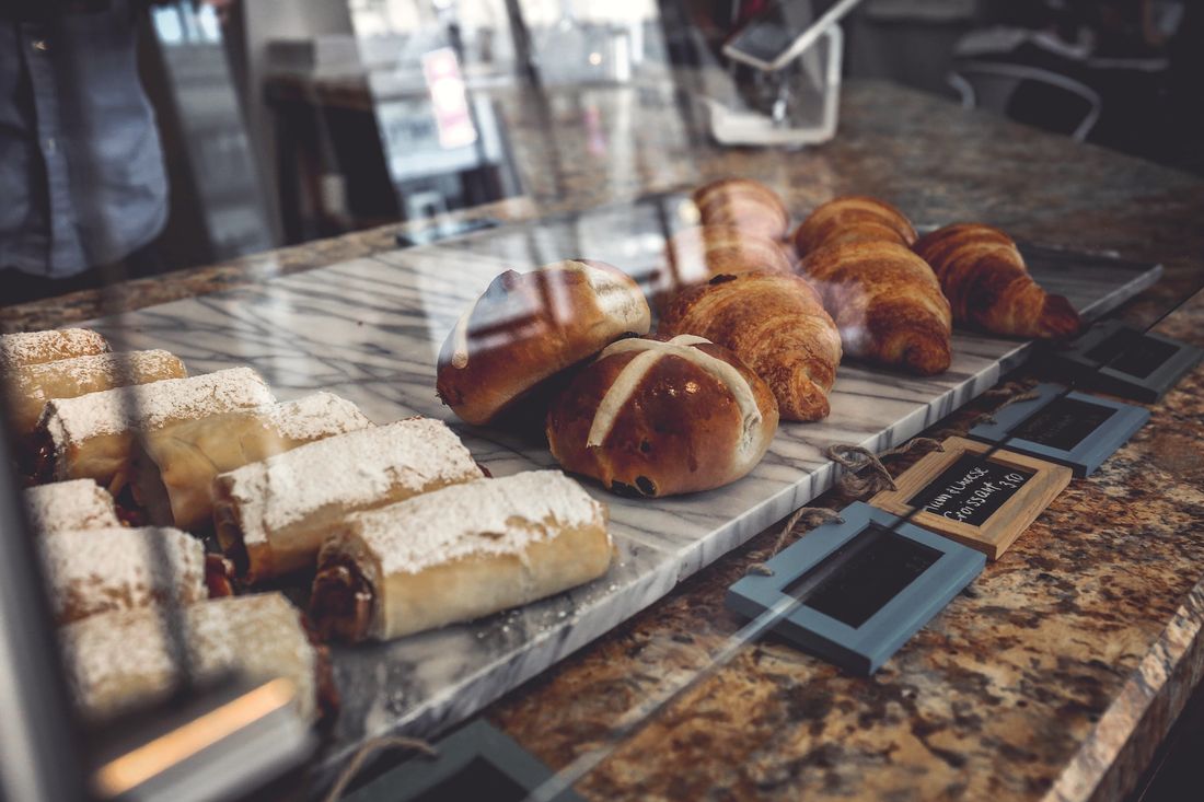 A bakery display case with croissants and loaves on the counter and shelves of baked goods behind