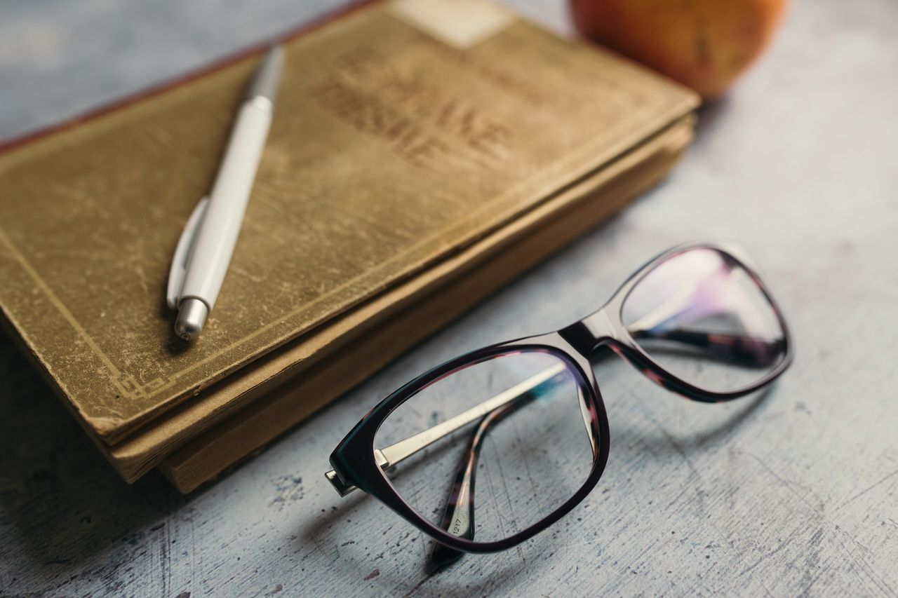 Notebooks, a pen and a pair of glasses on a wooden desk