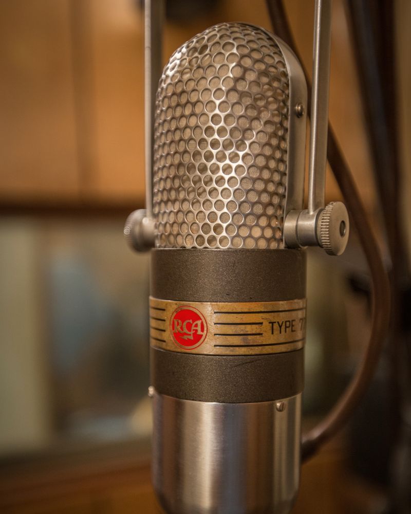 A vintage ribbon microphone on a stand against a dark background