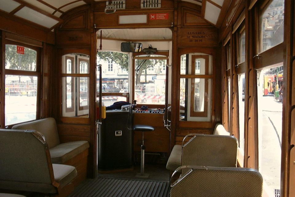 The wooden interior of an old Lisbon tram, empty seats and brass rails