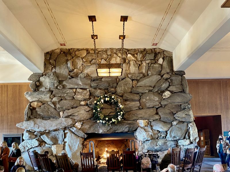 A dining room with a large stone fireplace and a hanging lantern