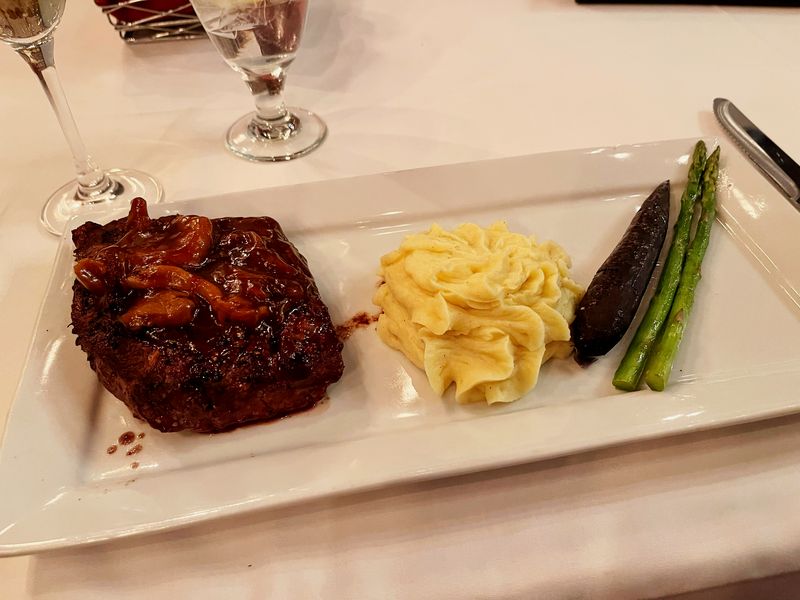 A steak with buttered noodles and asparagus on a white plate