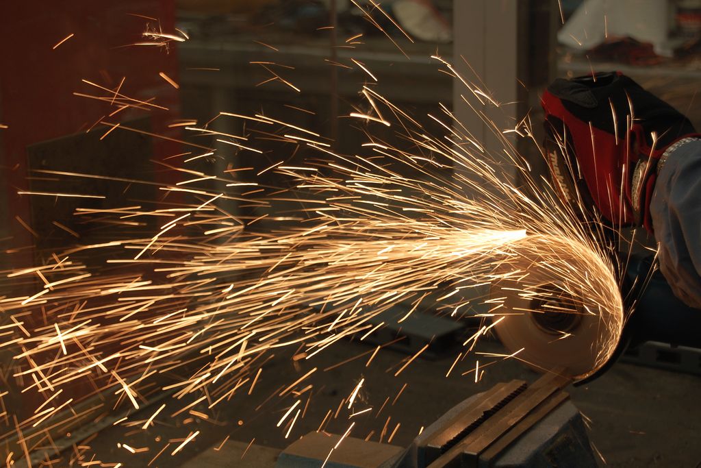 An angle grinder throwing a fan of sparks as it cuts steel
