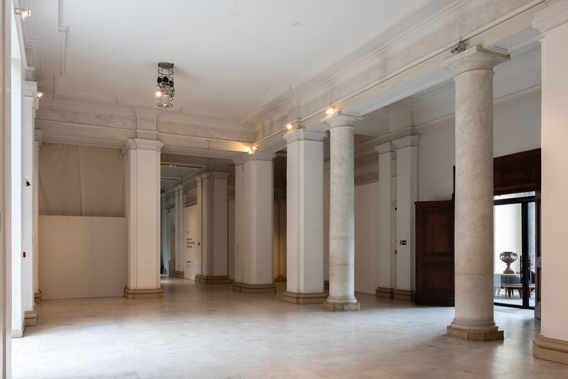An empty gallery hall with stone columns and a polished floor