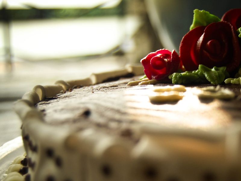 Close view of an iced cake decorated with red sugar roses