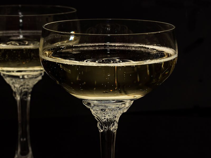 Two coupes of champagne against a dark background
