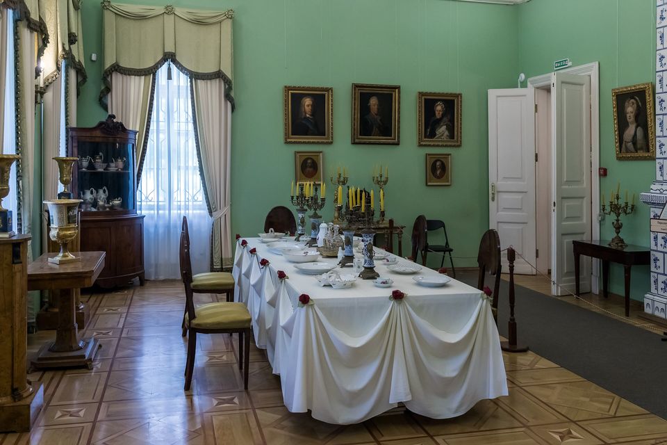 A green-walled dining room with a long table laid in white linen