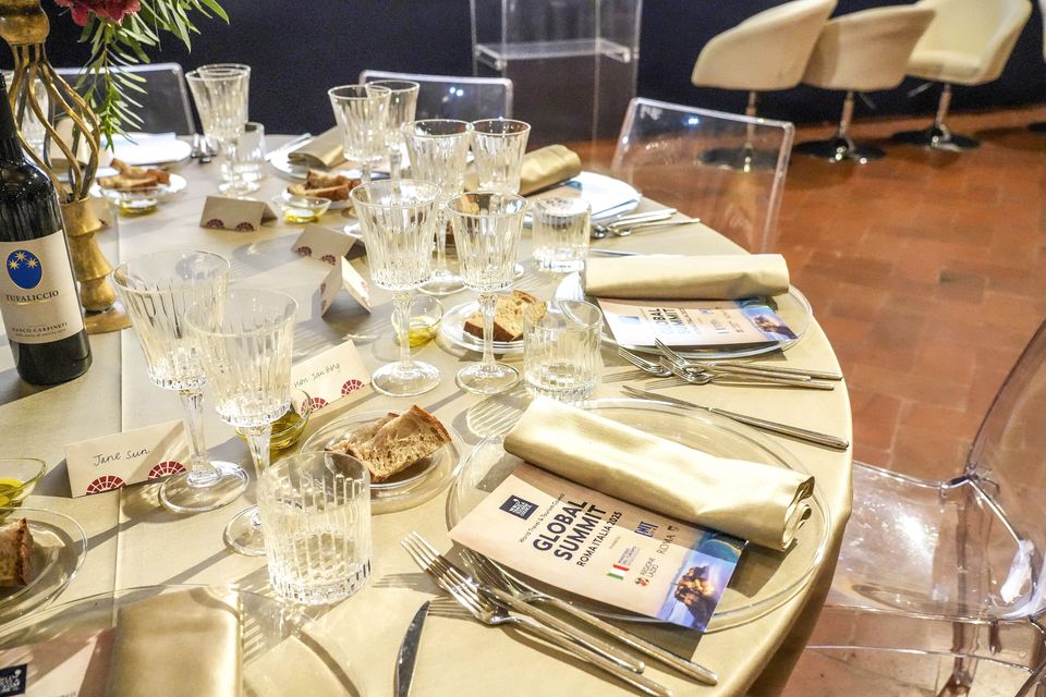 A round dinner table laid with glasses, folded napkins and printed booklets