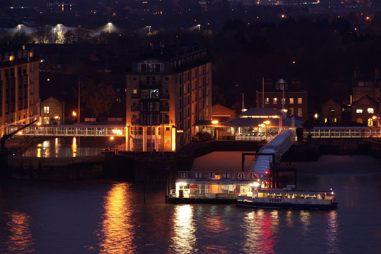 The River Thames at night, with lit buildings and a boat on the water