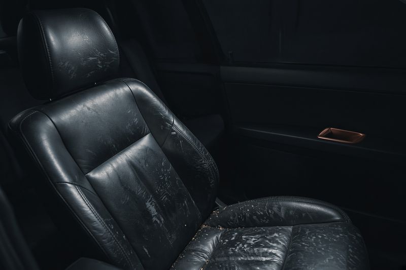 Stained dark leather seat before an interior clean