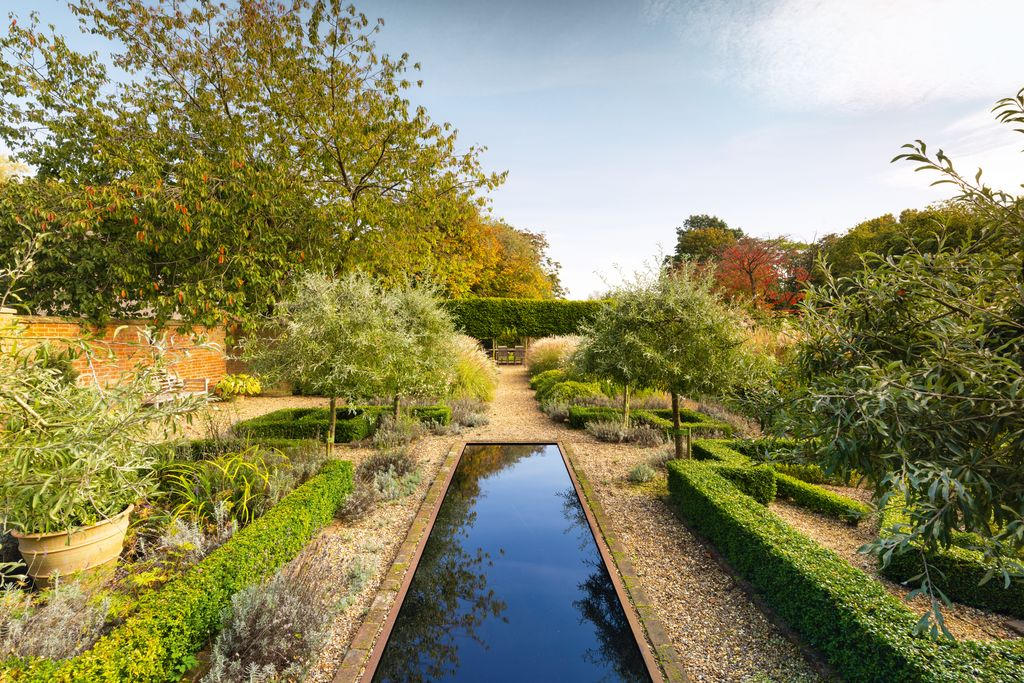 A narrow reflecting rill between clipped hedges