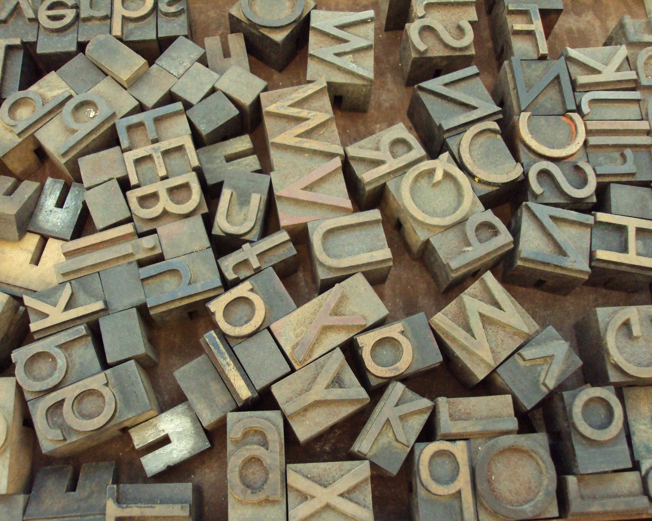 A heap of worn wooden letterpress type, letters facing up