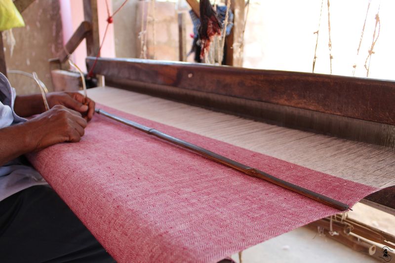 A length of pink cloth on a wooden weaving loom