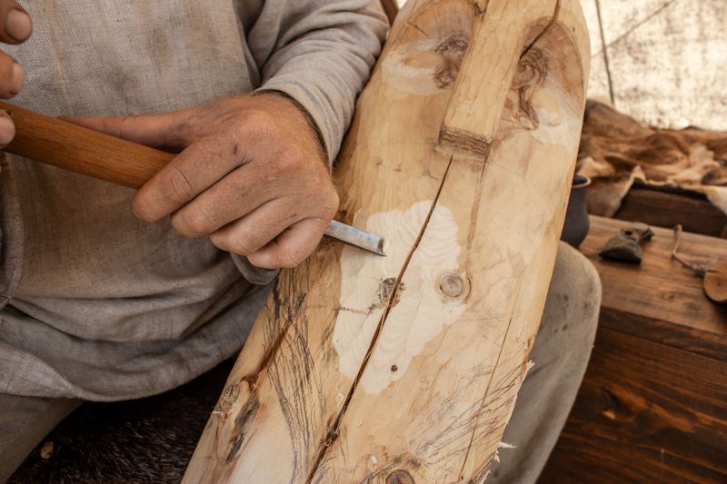 Hands carving a piece of wood with a knife