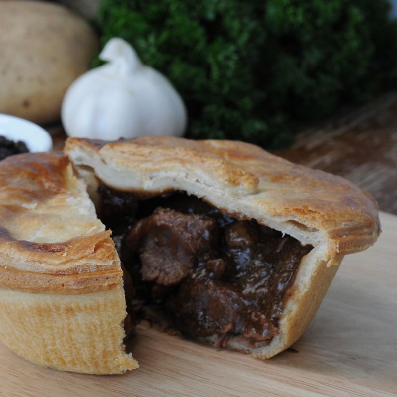 A steak and ale pie cut open on a wooden board