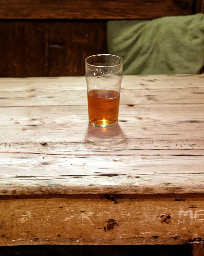 A glass of beer alone on an old scrubbed wooden pub table