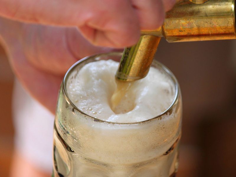 A glass filling with foaming beer under a brass tap