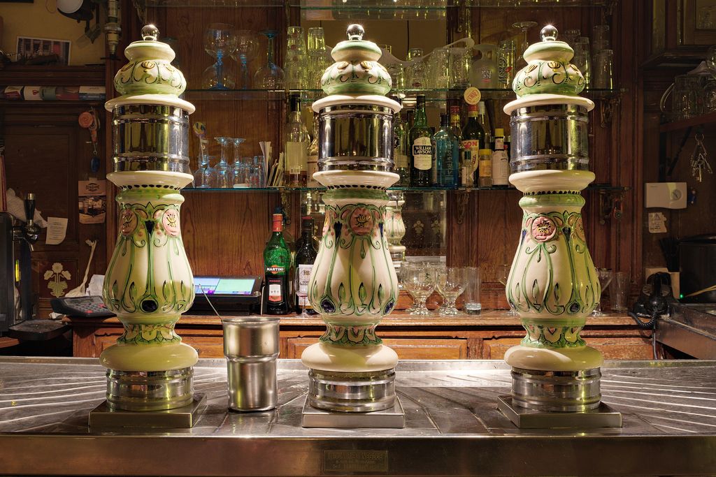 Three ornate ceramic beer pumps on a pub bar