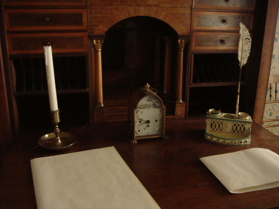 An old writing desk with a candle, an inkwell and paper