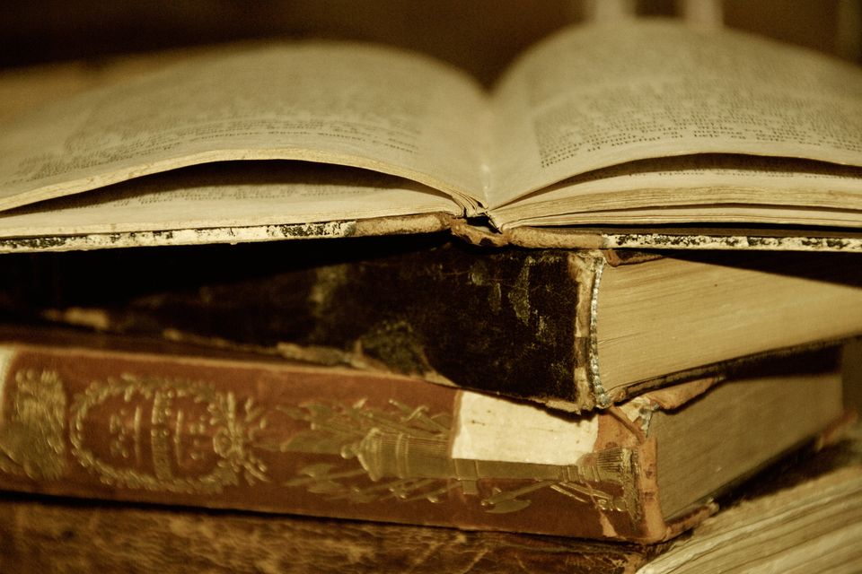 A pile of old books, the top one lying open