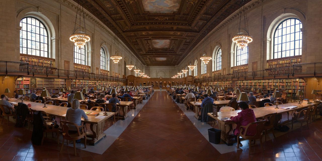A long public-library reading room with rows of reading tables