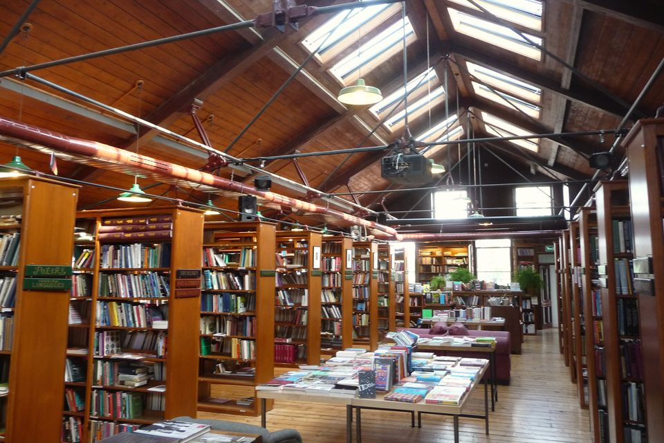 A bookshop room under skylights, with long rows of shelves