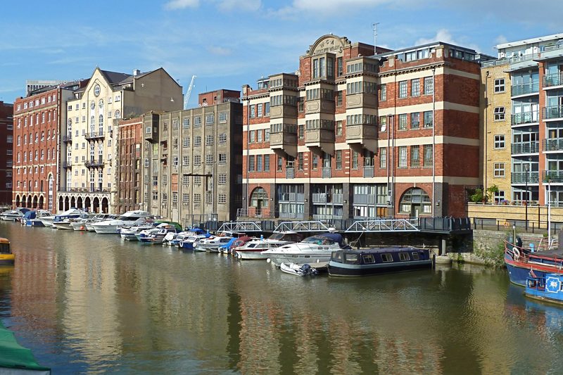 Harbour lined with brick warehouse apartments and moored boats