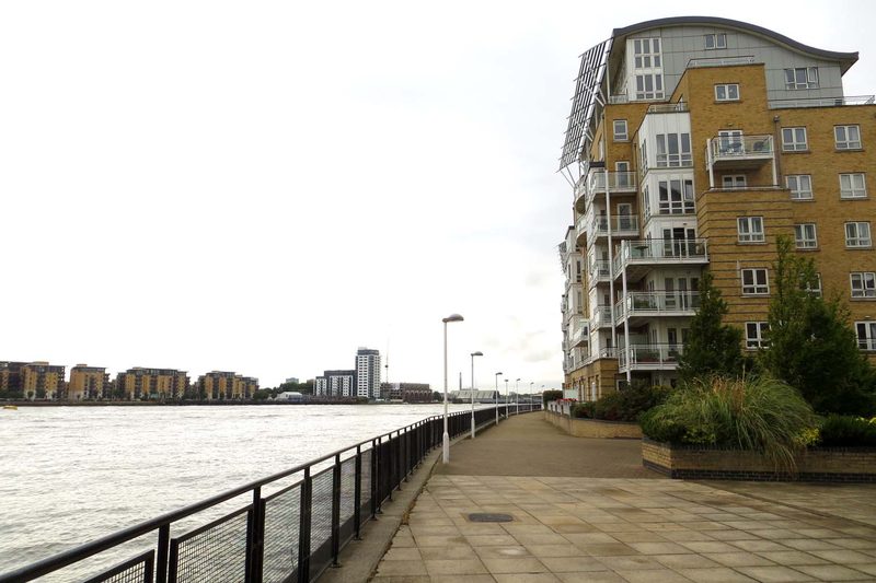 Riverside path with railings and a modern apartment building by the water
