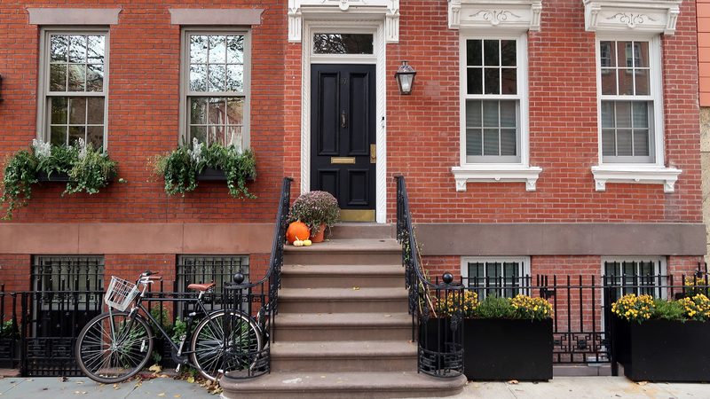 Red-brick townhouse with a black front door, white stone steps, iron railings and window boxes