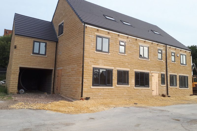 New-build three-storey houses in buff brick with dark grey window frames