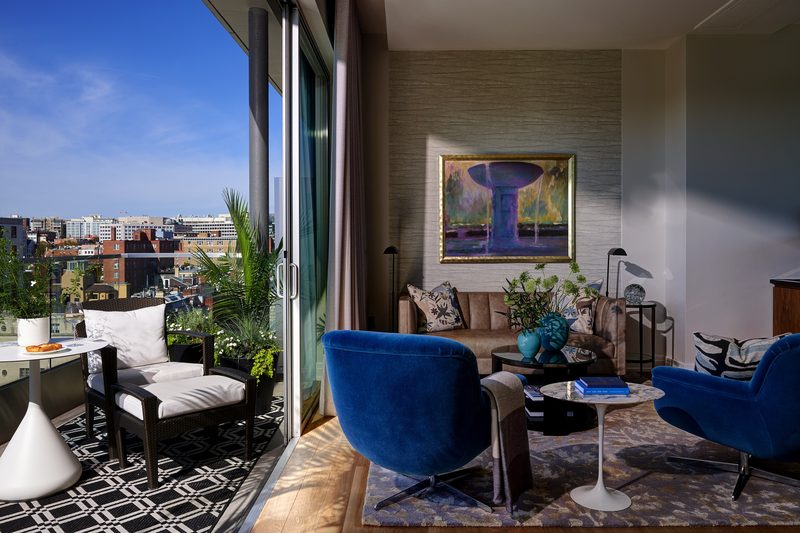 Penthouse living room with blue armchairs opening onto a planted roof terrace