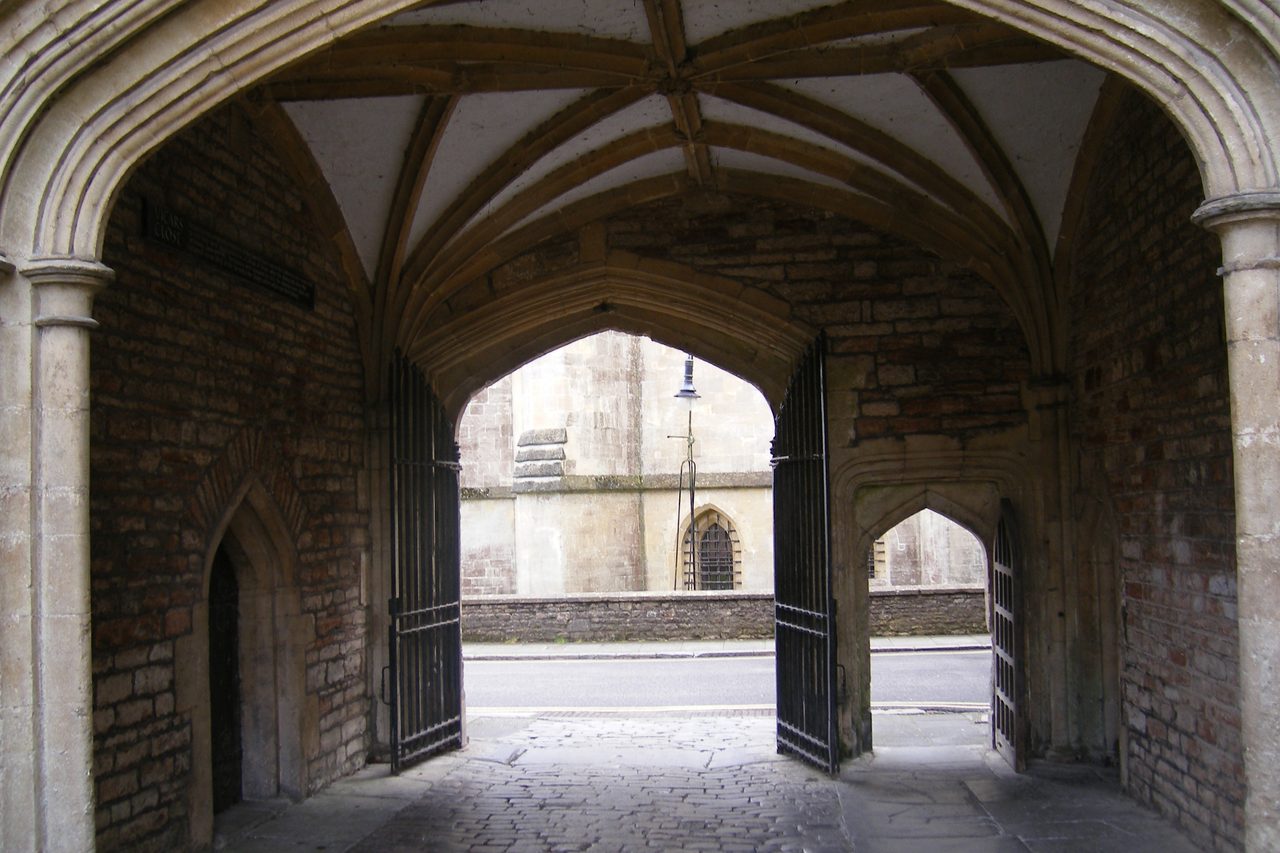 A vaulted stone gateway opening onto a sunlit courtyard